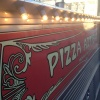 The red and gold Pizza Artisan livery on the side of the van, lit up at night